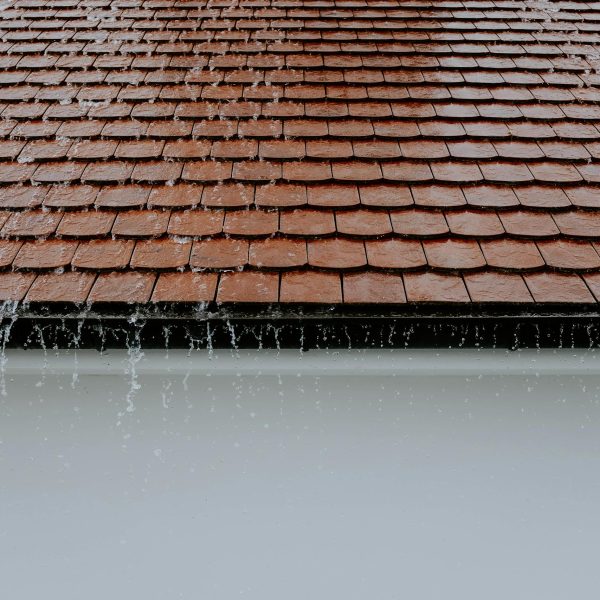 brown-roof-tiles-with-rainwater-cascading-down-showcasing-architectural-texture-and-detail-2663254-scaled